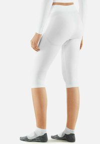 Witte, knielange leggings met een aansluitend ontwerp. De stof lijkt glad en rekbaar, met een subtiele glans en geribde textuur.