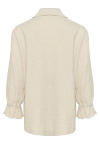 Camicia beige chiaro con colletto, maniche lunghe a sbuffo e polsini a rouche elasticizzati. Realizzata in un tessuto leggero e testurizzato.