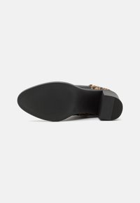 Suela de zapato de goma negra con un patr�ón texturizado, que presenta una parte superior de leopardo marrón y un tacón bajo y cuadrado para mayor estabilidad.