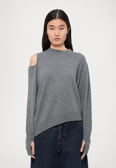 Grijze gebreide trui met een hoge hals, lange mouwen en een open schouderdetail. Zachte textuur en een relaxte pasvorm, gecombineerd met donkere jeans.
