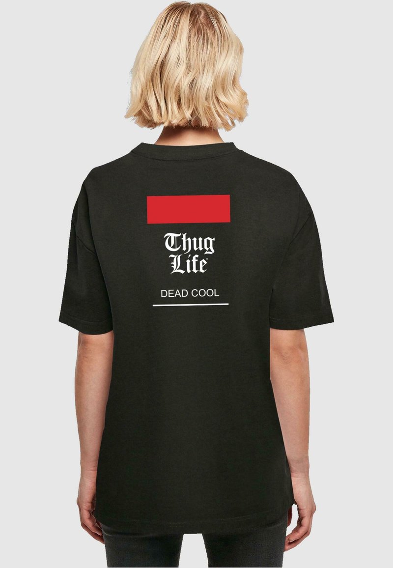 Juodas trumpas rankovė t-shirt, turintis raudoną stačiakampį akcentą ir baltą tekstą: "Thug Life" virš "DEAD COOL" ant nugaros.