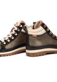 Botas de senderismo de cuero marrón y olivo con un cuello crema contrastante, acentos en rosa, ojales plateados y suela de goma crema resistente.