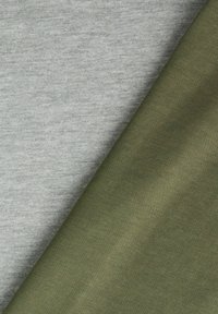 Διπλωμένα κομμάτια υφάσματος σε ανοιχτό γκρι και ελαιόλαδο με ορατή πλεκτή υφή και διαγώνια στρώση.