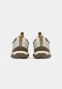 Beige and olive outdoor shoes with a textured sole, rear pull tabs, and light blue accents. Designed for traction and comfort.