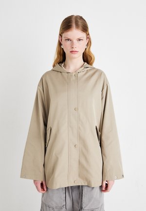 Beige lett jakke med hette, trykknappslukking, sidelommer og løs passform. Glatt tekstur og minimalistisk design.