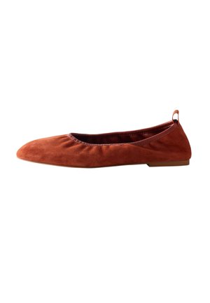 Bruine suède platte balletschoen met afgeronde neus, lage hak en stoffen trekervaring bij de hiel, getoond in zijprofiel tegen een witte achtergrond.