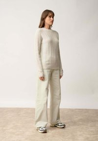 Vaaleanharmaa ribattu neulepaita, jossa on pitkät hihat, yhdistettynä vaaleanvihreisiin leveälahkeisiin housuihin ja teksturoituihin tennareihin. Minimalistinen muotoilu, pehmeä kangas.