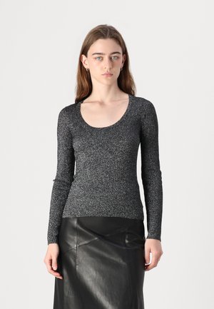Langermet svart ribbestrikket topp med rund hals, laget av skinnende, teksturert stoff. Kombinert med et svart skinnskjørt.