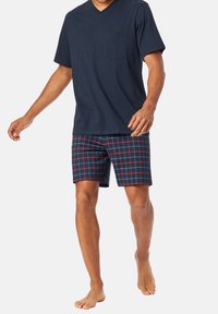 Tricou de culoare bleumarin cu decolteu în V, mâneci scurte și un buzunar pe piept, asociat cu pantaloni scurți în carouri de bleumarin, roșu și alb, având o croială normală.
