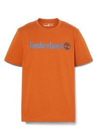 Orange bomulds t-shirt med korte ærmer, rund halsudsk�æring og blå "Timberland" tekst ved siden af et trælogo. Glat tekstur, afslappet design.
