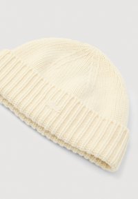 Kremowy, ręcznie robiony beanie o ryflowanej fakturze, z podwiniętym mankietem i subtelnym logo po boku.