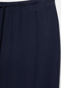 Navyblauwe broek met elastische tailleband en klein geborduurd logo vlakbij de taille aan de rechterkant, gemaakt van zachte stof.