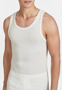 Top in cotone a coste di colore bianco, con scollatura a giro e spalline larghe. Texture liscia, design aderente.