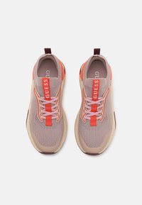 Baskets en mesh rose et orange avec semelles en caoutchouc beige contrastant. Présentent un logo "GUESS" bien visible et des lacets fins. Design à bout arrondi.