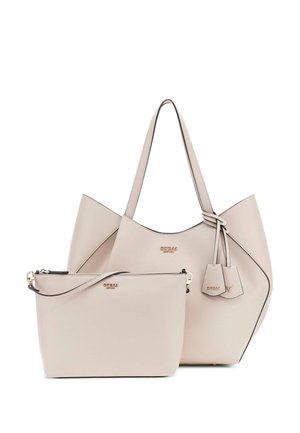 Sac fourre-tout synthétique beige avec double poignées, présentant un détail de nœud et des étiquettes décoratives. Comprend une petite pochette zippée assortie.