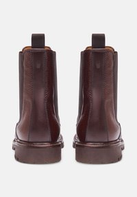 Stivali alla caviglia in pelle marrone con pannelli laterali elasticizzati, finitura testurizzata e suola robusta marrone. Anelli posteriori per un facile indossamento.