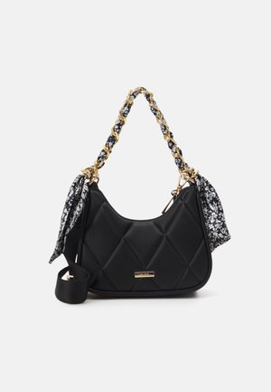 Czarna pikowana torebka na ramię z złotym łańcuszkiem plecionym z czarno-białej kwiatowej tkaniny oraz pasującymi tkaninowymi wiązaniami po obu stronach.