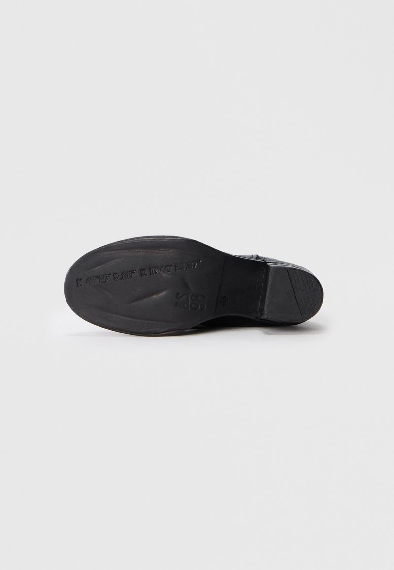 Semelle de chaussure noire avec surface texturée, léger talon et marquage en relief. Matériau lisse avec bords arrondis ; pas de motifs ou d'accents visibles.