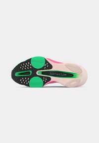 Nike Flyplate shoe sole in black and pastel pink, featuring green circular accents and textured rubber for grip, with a smooth pink midsole.