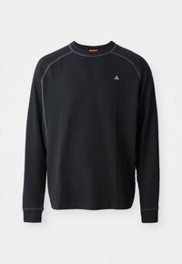 Schwarzes Langarmshirt aus strukturiertem Stoff. Verfügt über einen Rundhalsausschnitt, Kontrastnähte und ein kleines Logo auf der Brust. Normale Passform.