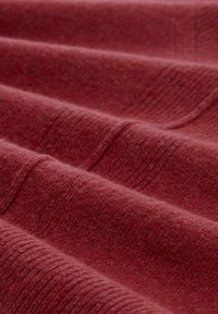 Textile fabric in deep red with a soft, textured surface featuring horizontal ridges and subtle variations in shade.