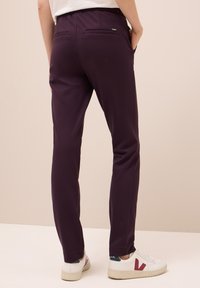Fialové slim-fit kalhoty s měkkou texturou a elastickým pasem. Obsahují dvě zadní kapsy a hladký, strukturovaný design. V kombinaci s bílými teniskami.