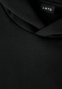 Schwarzer Hoodie aus weichem Stoff, mit einem eng anliegenden Kragen und einem Etikett mit der Aufschrift "LMTD." Glatte Textur ohne Muster oder Akzente.