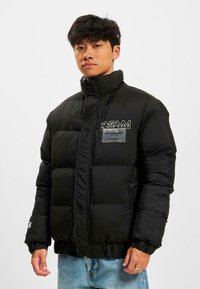 Jachetă neagră căptușită cu guler înalt, închidere cu fermoar și mansete elastice. Prezintă un patch cu logo pe piept și un material texturat pentru un plus de căldură.