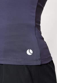 Marineblå treningstopp med tettsittende design, laget av glatt stoff, med en avrundet logo i hvitt på den nedre sømmen.