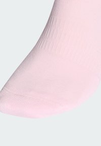 Hele roosa pahkluu sokk soonilise mansetiga ja sileda varbaõmbluse detailiga, taustal valge ühtlane pind.