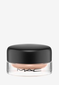 Producto en crema de MAC en un frasco de vidrio transparente con tapa de plástico negro. El contenido es de un tono melocotón suave. Presenta el logo de MAC.