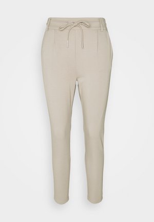 Pantalon beige fuselé avec taille à cordon et passants pour ceinture, présenté sur un fond clair uni.