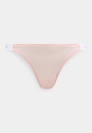Világos rózsaszín tanga sima anyagból, fehér derékpánttal, finom márkajelzéssel. Egyszerű kialakítás, minimális varrással és díszítések nélkül.