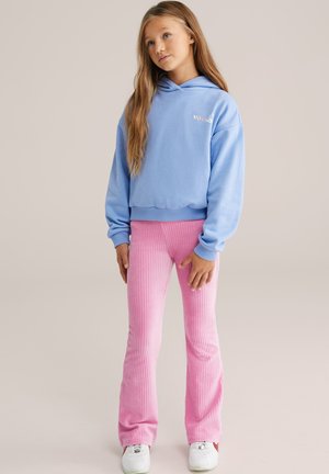 Cropped hoodie azzurro con logo, abbinato a pantaloni flared rosa a costine. Sneakers bianche completano l'outfit. Tessuto morbido e stile casual.