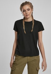 T-shirt en coton noir à manches courtes, avec un col rond et une coupe décontractée. Associé à un pantalon cargo vert olive. Design simple, sans motifs.