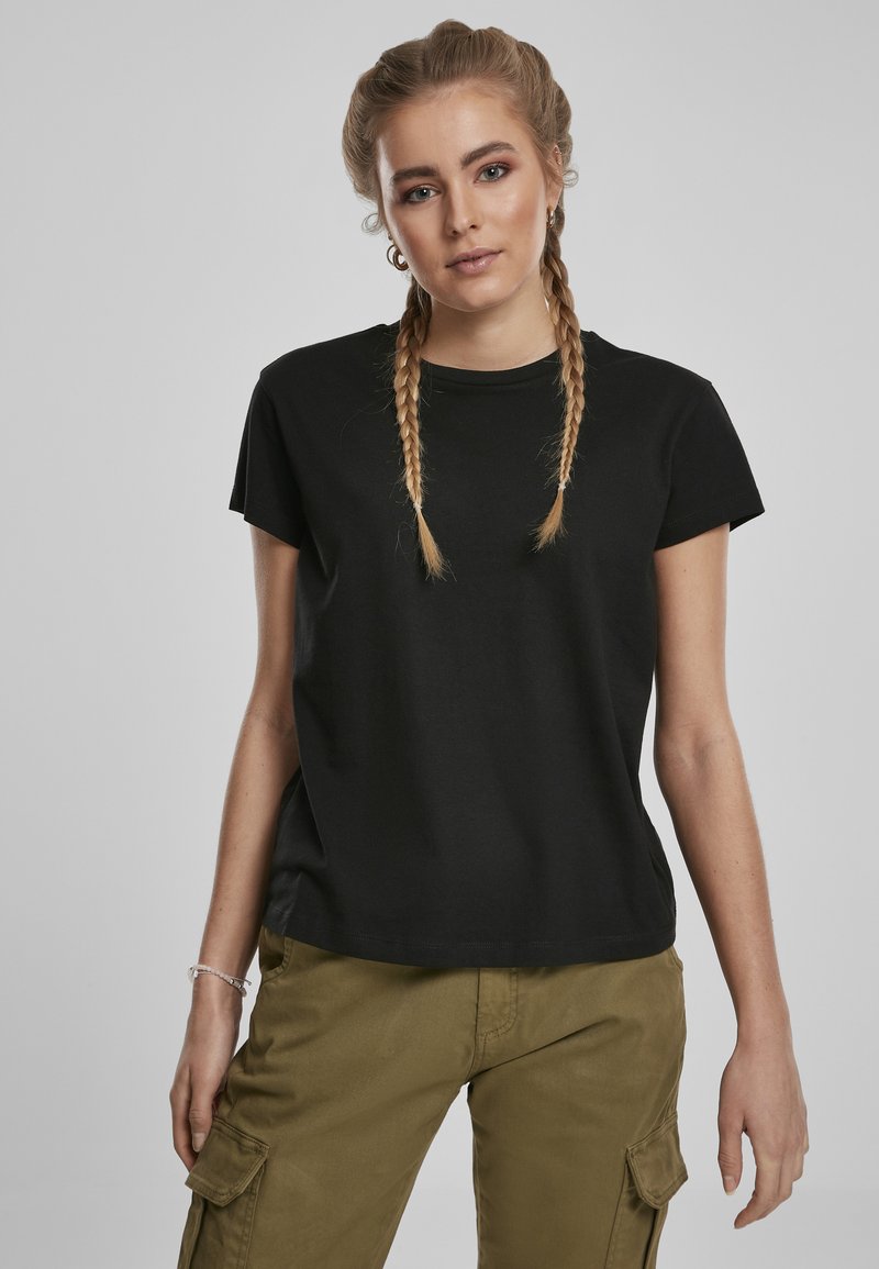 T-shirt en coton noir à manches courtes, avec un col rond et une coupe décontractée. Associé à un pantalon cargo vert olive. Design simple, sans motifs.
