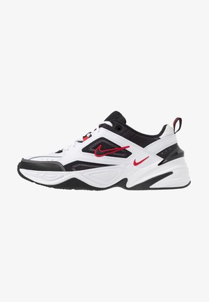 Białe, czarne i czerwone buty Nike z siateczkową i skórzaną cholewką, grubą podeszwą, czerwonymi logo Swoosh i tylną pętlą do ściągania.