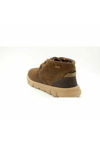 Scarpa alta in suede marrone con suola in gomma beige, caratterizzata da una fodera interna a fantasia e un accento marrone vicino al tallone con il logo Jeep.