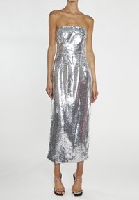 Robe de soirée sans bretelles, ornée de sequins argentés, silhouette ajustée, longueur genoux, texture lisse, coutures plates, portée avec des sandales noires à talons.