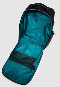 Zaino nero con interno aperto turchese, che presenta una tasca in rete e un compartimento con cerniera, evidenziando il suo design spazioso e la disposizione funzionale.