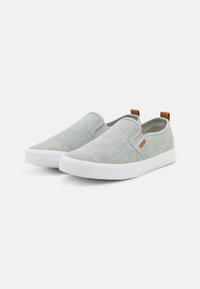 Szürke, texturált anyagból készült, slip-on cipők, fehér gumitalppal és kis barna díszítéssel a sarkon.