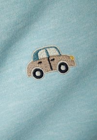 Svetlo modrá látka má malý vyšitý dizajn auta v béžovej farbe, s modrou strechou, čiernymi kolesami a detailmi pre okná a svetlá.