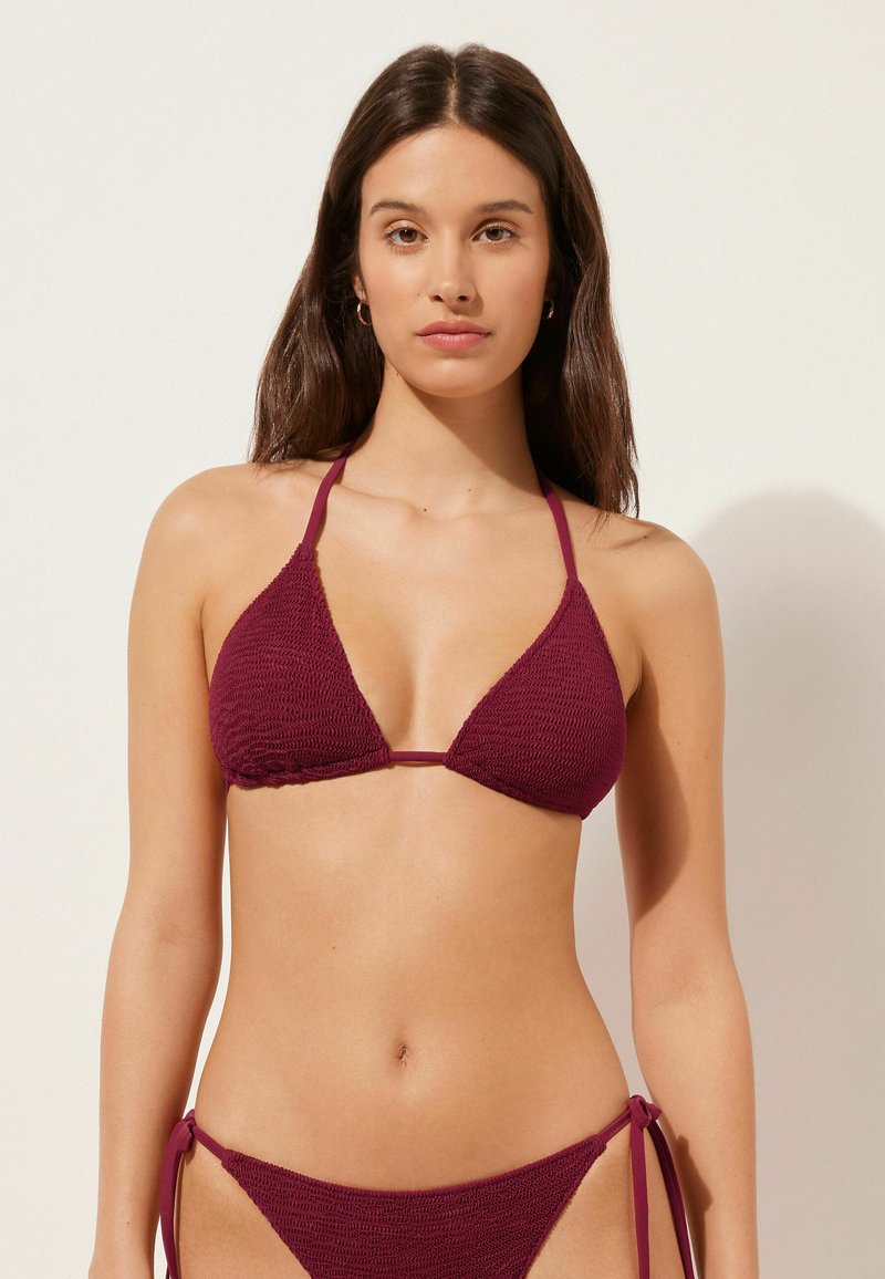Burgunderfärgad stickad bikiniöverdel med triangulära koppar och tunna remmar, med en texturerad finish. Matchande högmidjade bikiniunderdelar med snörningar.