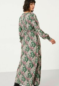 Maxikleid mit floralem und geometrischem Muster in Grün, Pink und Creme, langen Ärmeln und taillierter Passform. Glatte Stoffoberfläche.