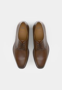 Scarpe eleganti in pelle marrone con una finitura liscia, punta arrotondata e design con lacci a cinque occhielli. Presentano un logo impressato sulla soletta, fatte in Italia.
