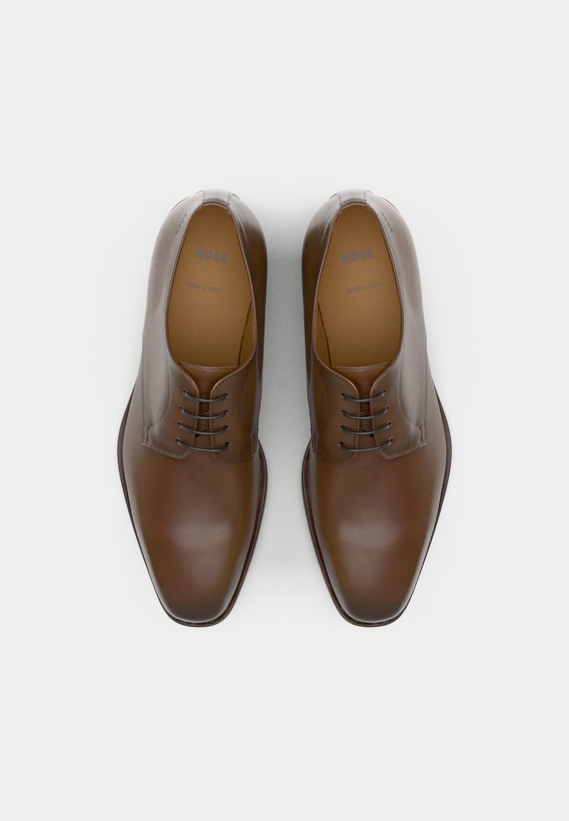 Chaussures habillées en cuir marron avec une finition lisse, bout rond et un design à laçage à cinq œillets. Présente un logo en relief sur la semelle intérieure, fabriquées en Italie.