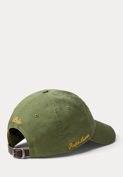 Καπέλο μπέιζμπολ από βαμβάκι σε ελιά πράσινο με κυρτή γείσο, κεντημένο με τις λέξεις «Polo» και «Ralph Lauren» σε κίτρινο. Ρυθμιζόμενο λουράκι από δέρμα στο πίσω μέρος.