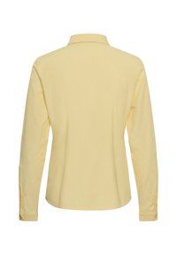Chemise jaune clair à manches longues avec col, vue de dos, avec poignets boutonnés et un tissu simple et lisse.