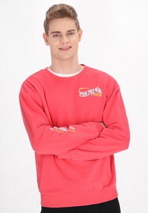Roter Pullover mit Rundhalsausschnitt, gerippten Bündchen und Saum; mit grafischem Text in Gelb auf der Brust und dem Ärmeln; aus Baumwollmaterial.