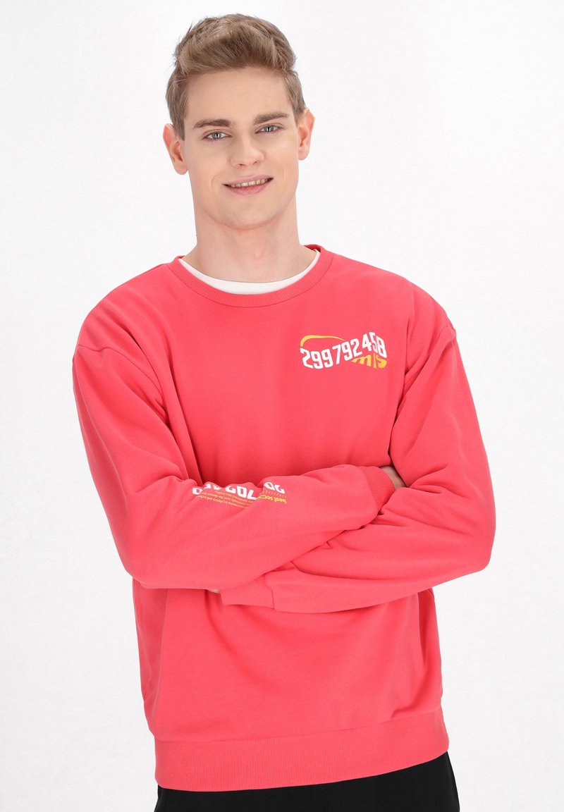 Rød sweatshirt med rund halsudskæring, ribbede manchetter og kant; har grafisk tekst i gult på brystet og på ærmet; lavet af bomuldsmateriale.
